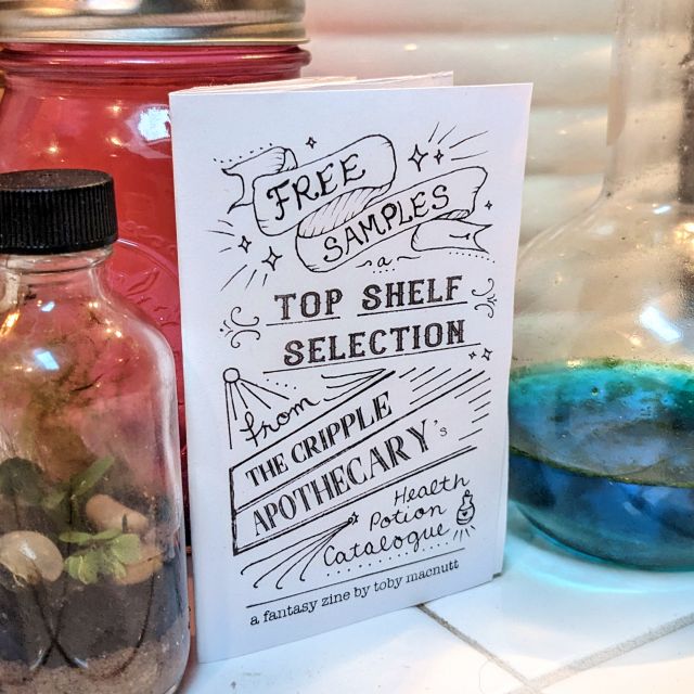 an eighth-fold zine with hand lettered title like an old timey sandwich board or carnival sign, posed among bottles and jars