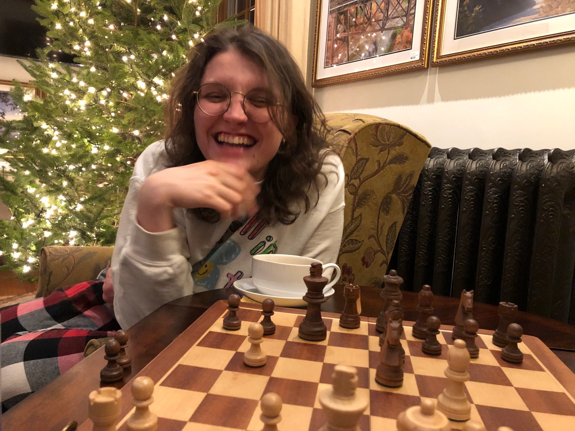 Jozef, a person with brown hair and glasses, sits in front of a chess board; there is a Christmas tree behind him