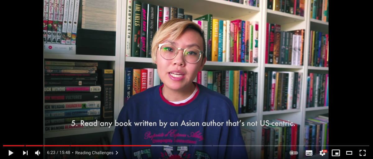 A screen grab of Cindy's Asian Readathon 2021 YouTube video. On the screen, at the bottom of Cindy facing the camera, mid-speech, is text that reads: "5. Read any book written by an Asian author that's not US-centric."