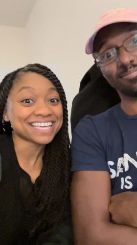 Still from a video. Rob and I grin into the camera, seated side-by-side.