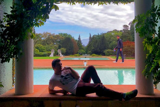 A photograph of me laying down with grace in front of a pond and a symmetrical garden