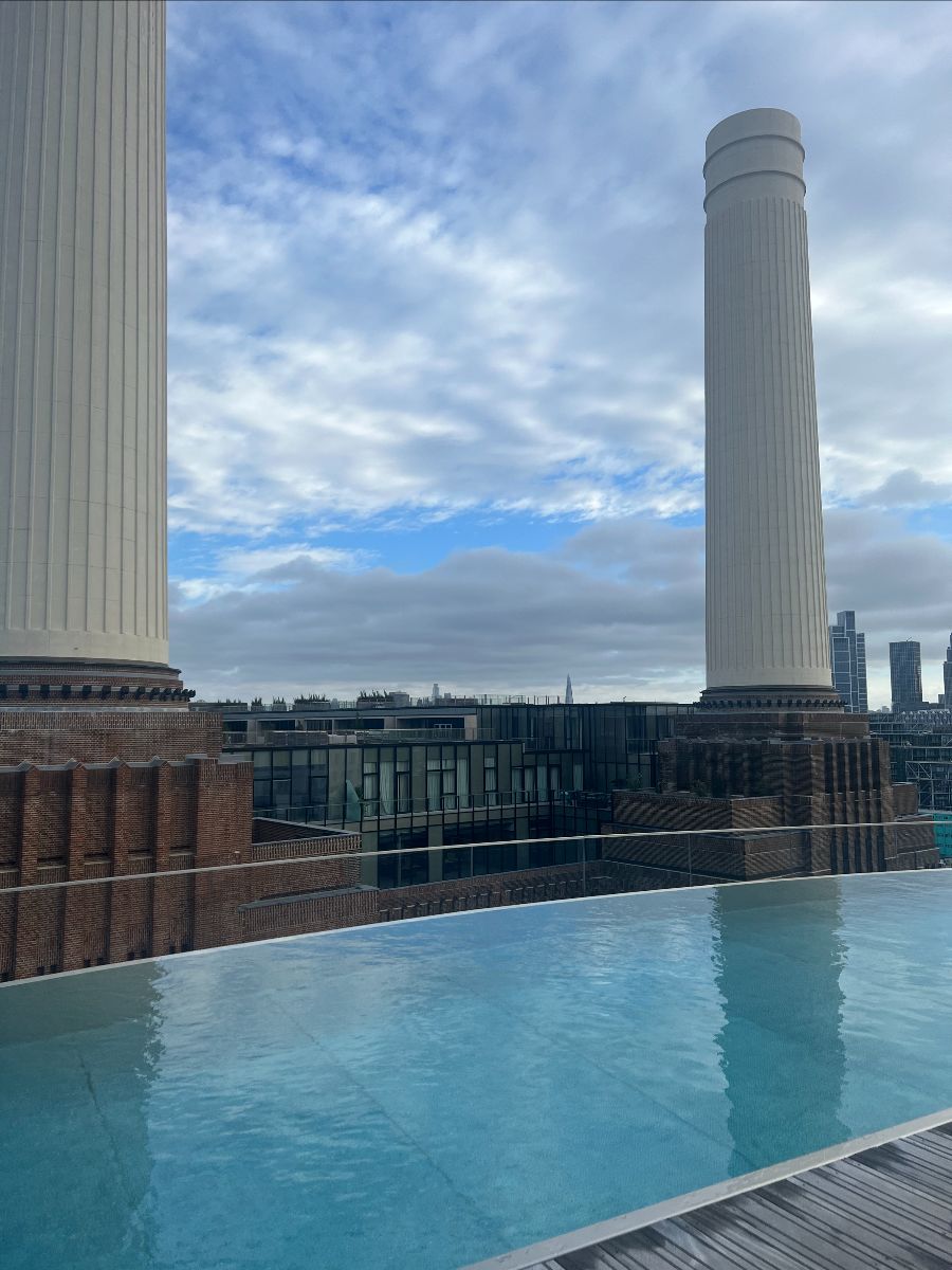 Imagine of a rooftop pool looking out onto the skyline, where buildings and two tall pillars are visible. 