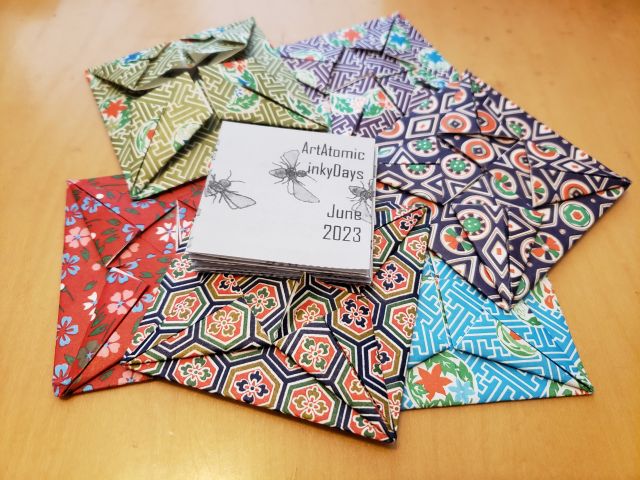 Assortment of origami paper packets with a micro-zine on top