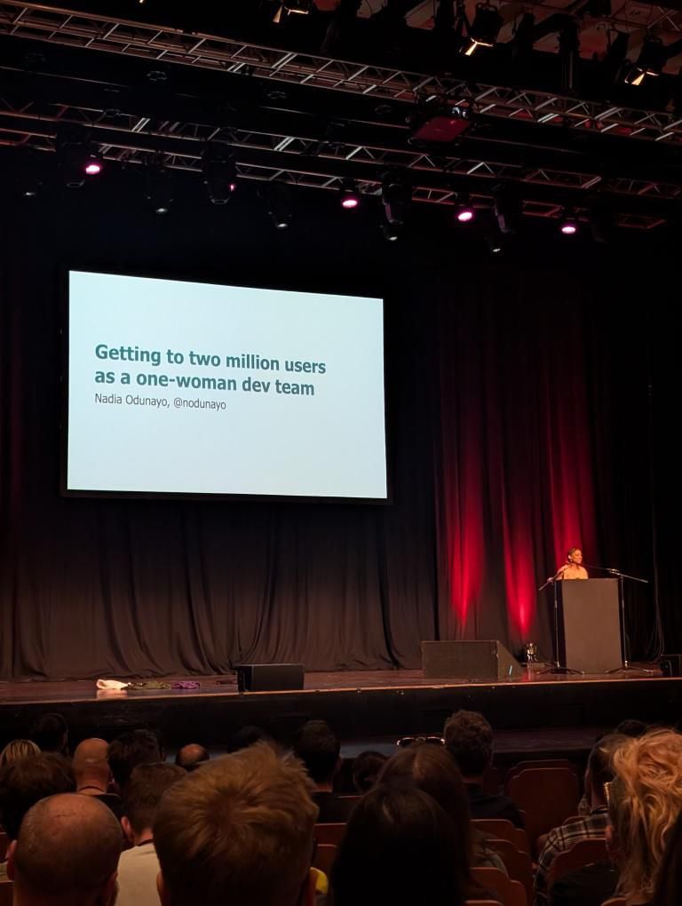 Photo of a conference stage. I'm standing behind a podium. There's a large slide up with the title of my talk and name on it.