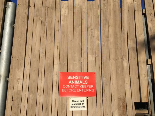 Large wooden gate. The sign reads "SENSITIVE ANIMALS: CONTACT KEEPER BEFORE ENTERING."