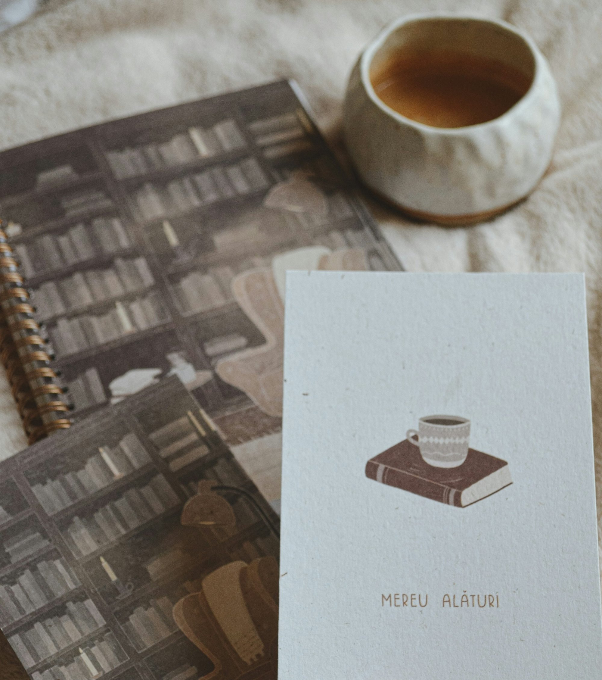 a hand holding a book next to a cup of coffee