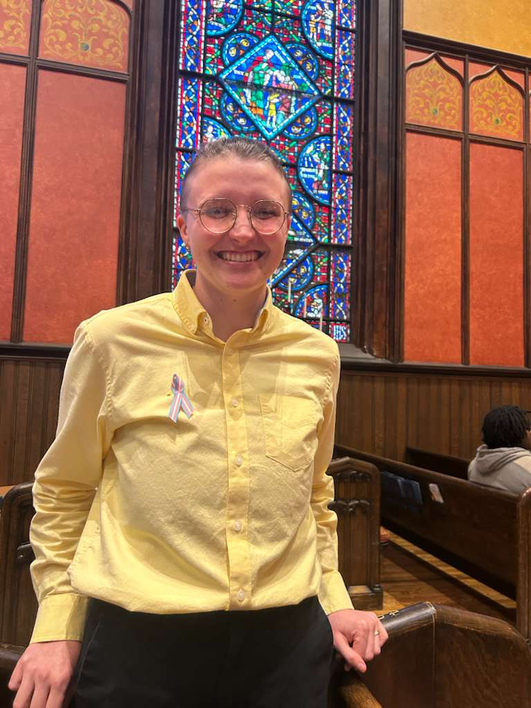 A photo of Jozef in his concert outfit, grinning in front of a stained glass window