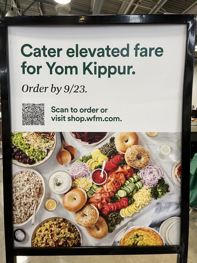 an in-store advertisement at Whole Foods, showing a grand buffet of food, telling people to cater for Yom Kippur