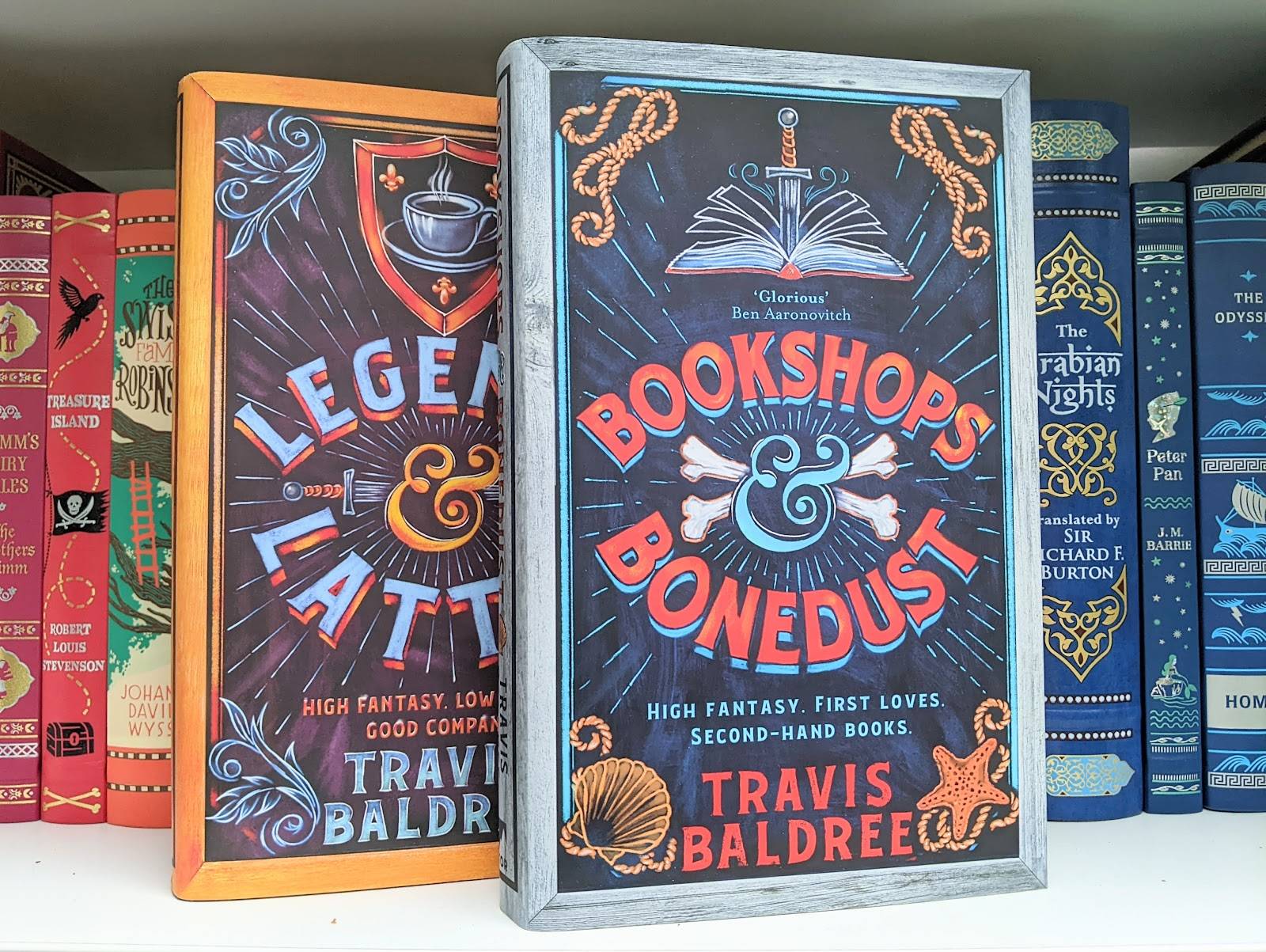 Books on a shelf with two volumes prominently displayed: Legends & Lattes and Bookshops & Bonedust, both high fantasy novels by Travis Baldree.