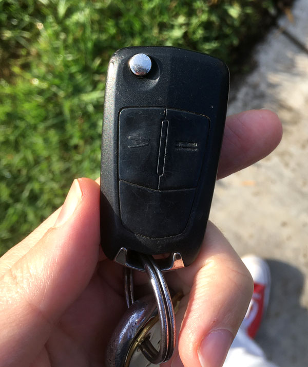 photo of a hand holding a late-model Saturn keyfob with two worn buttons, unlock and lock