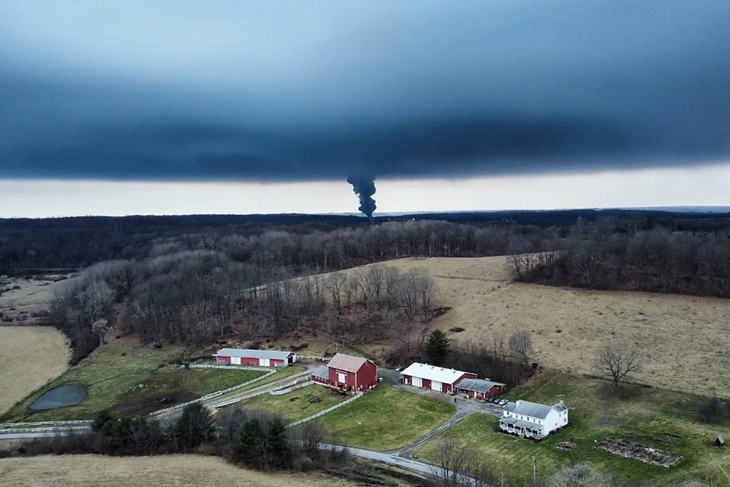 A thick plume of black smoke seen from a distance over farmland. A thick plume of black smoke seen from a distance over farmland.