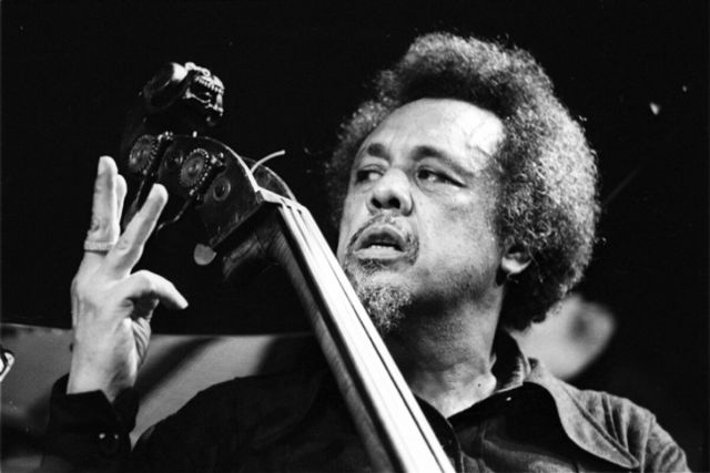 Charles Mingus holding up three fingers to someone out of shot