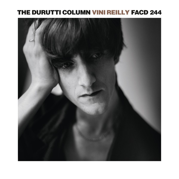 A sharp, well-executed black and white photograph of The Durutti Column's Vini Reilly (yes he named the album after himself.) The photo is a close-up, from the shoulders up. Reilly has a very long thin angular face, with long thick brown bangs crowning his head. He has thin lips and a cleft chin. He looks to the right with his hand holding up his head. He has a thoughtful look on his face. Imagine if Iggy Pop had a Shelleyan Romantic poet brother, that's what he looks like.