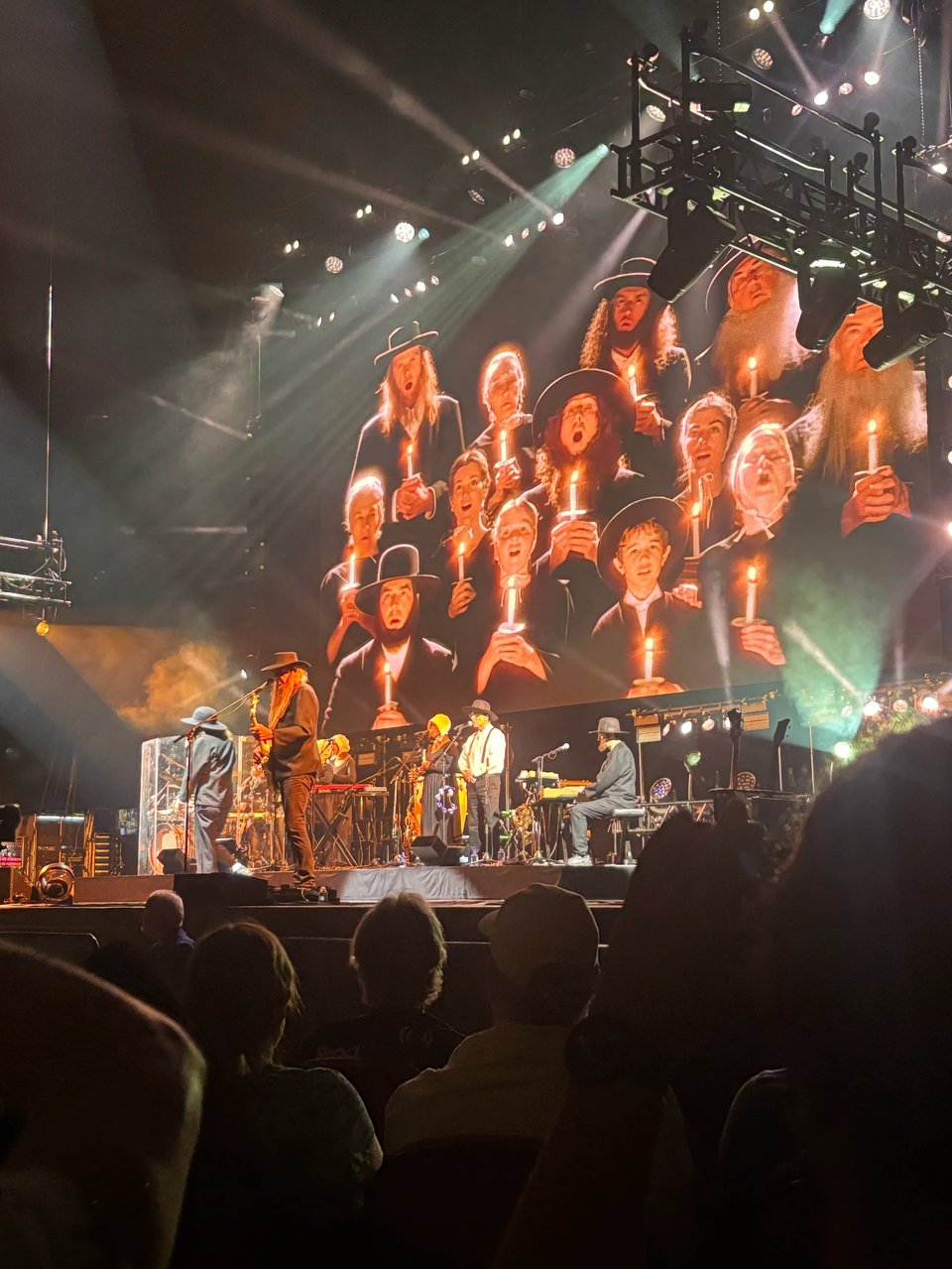 Weird Al Yankovic on stage in Miami with his band dressed like Amish folks, with a video screen showing Amish folks chanting with candles