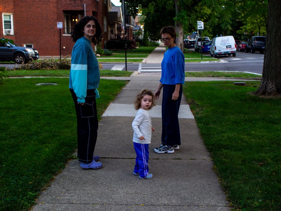Kat, Sona, and Bonnie stand on the sidewalk, all looking back at the camera. A loud noise had just happened behind me.
