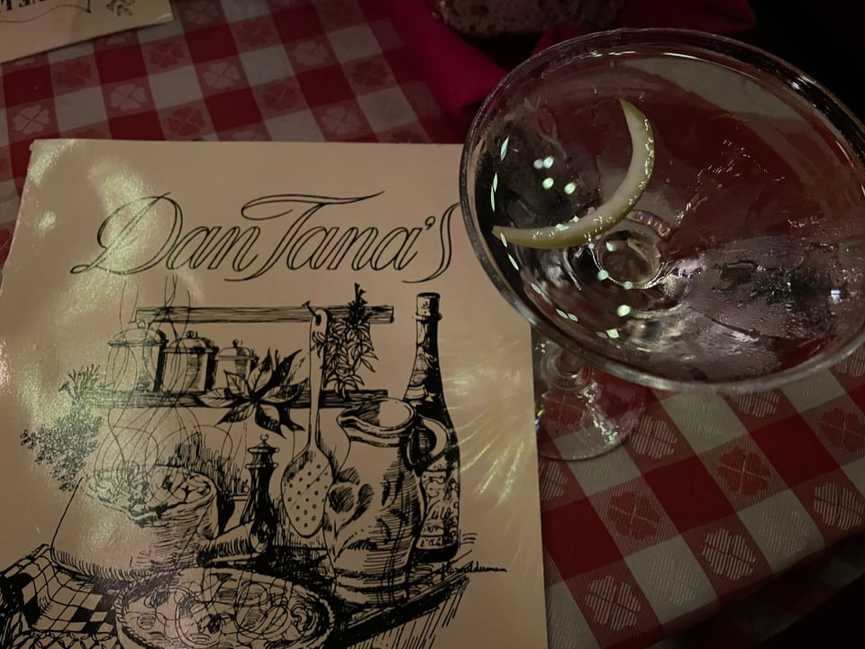 A close-up photo of an Italian restaurant menu that reads Dan Tana's and a martini with a smiling slice of lemon peel