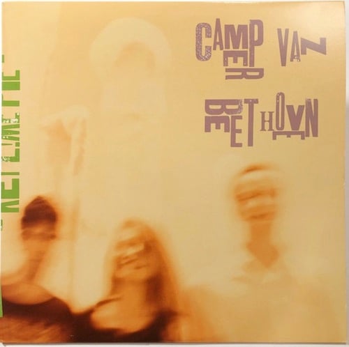 A extremely blurry photograph of three smiling people, presumably members of Camper Van Beethoven. They appear to be standing in front of some kind of statue, but the picture is so blurry and overexposed and manipulated that I'm not sure what it is or even if it's really there. The overall color of the photo is an extremely light brown-orange.