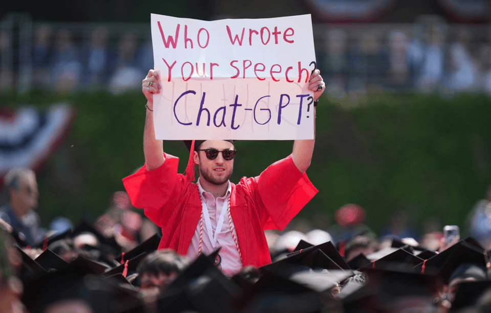 A picture of a student holding up a sign saying :"Who Wrote your Speech? ChatGPT?" - Photograph: Steven Senne/AP, via The Guardian