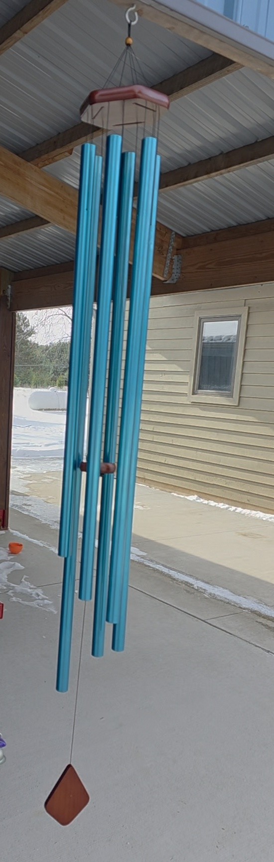 Windchime with long, round aluminum tubes of various lengths, which are suspended from a wooden hexagon with rounded edges.