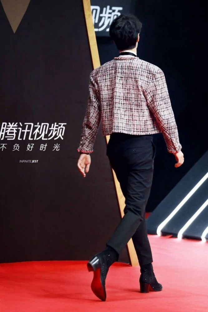 Famous photo of Wang Yibo exiting the red carpet in a perfectly cut matador-style jacket/pants combo (colorful chanel jacket, black pants) that accentuates his ass and especially the red soles of his high-heeled Louboutin boots. Iconic strut, iconic look, iconic shoes, iconic image.