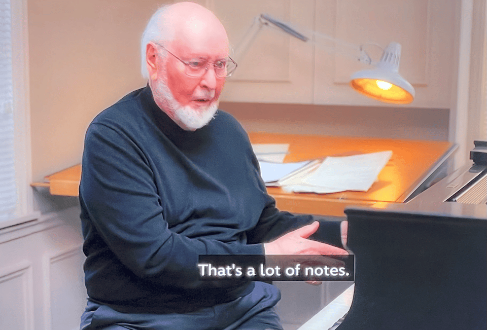 A screen capture of John Williams pointing at a piano with the subtitle That's A Lot of Notes