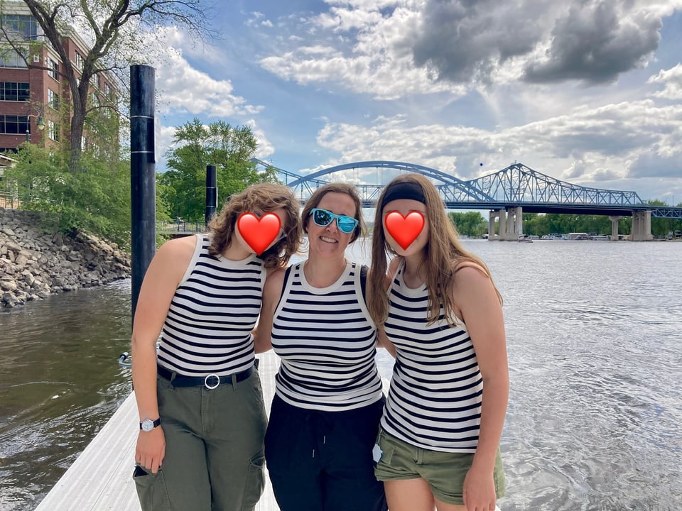 Katy and her two daughters by the Mississippi River in matching tank tops.
