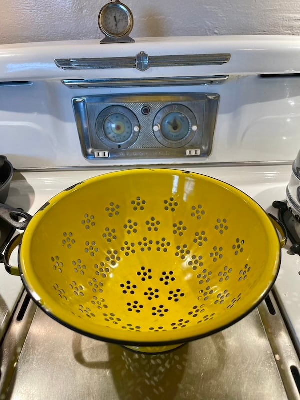 a yellow colander on top of a stove