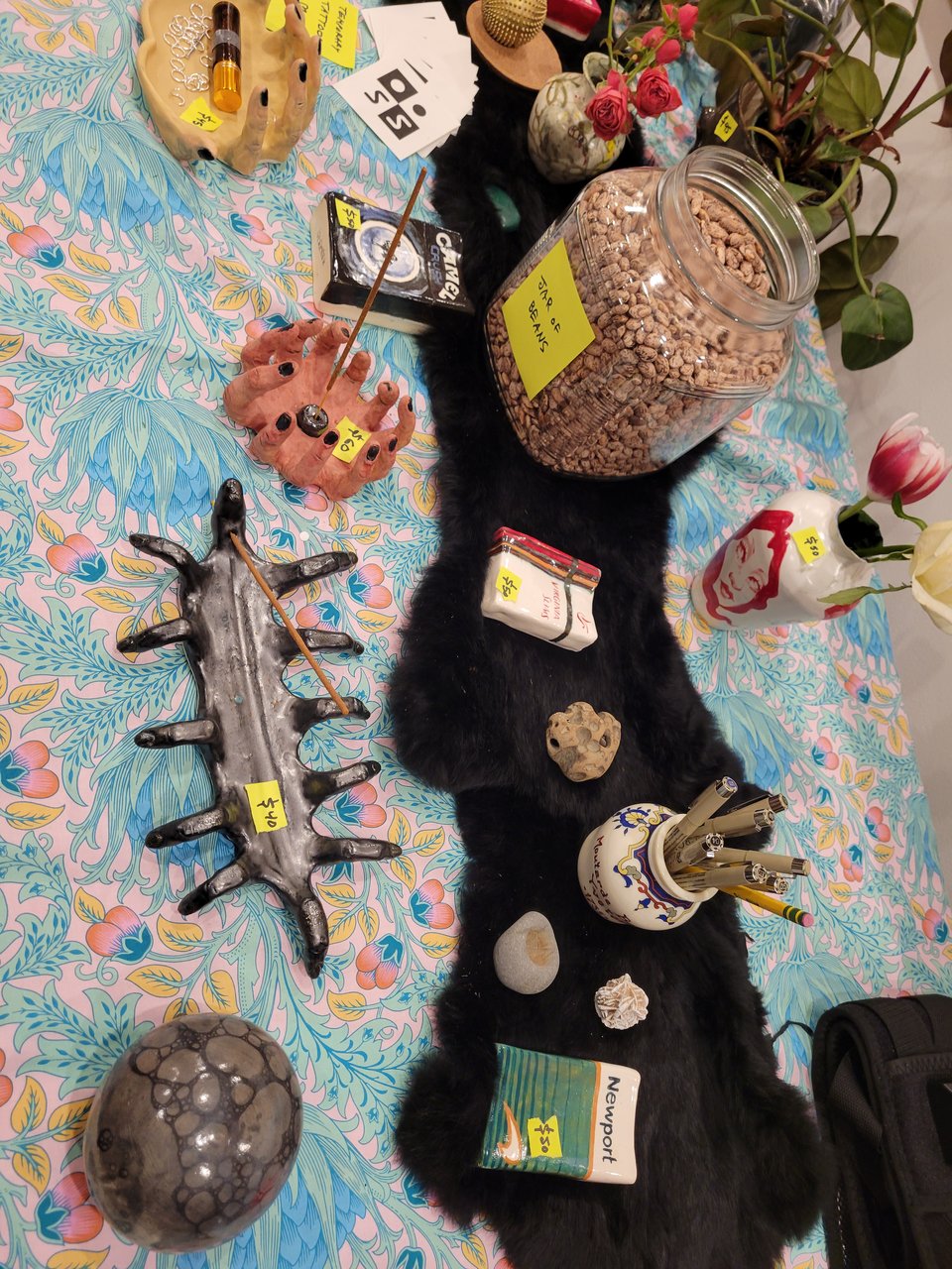 a table full of sensory experiences: spiky ceramics, a jar of beans, plants, pens, and more