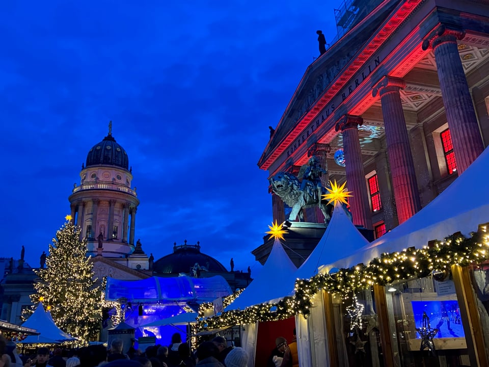 Lit tents and Christmas tree under a twilight sky.
