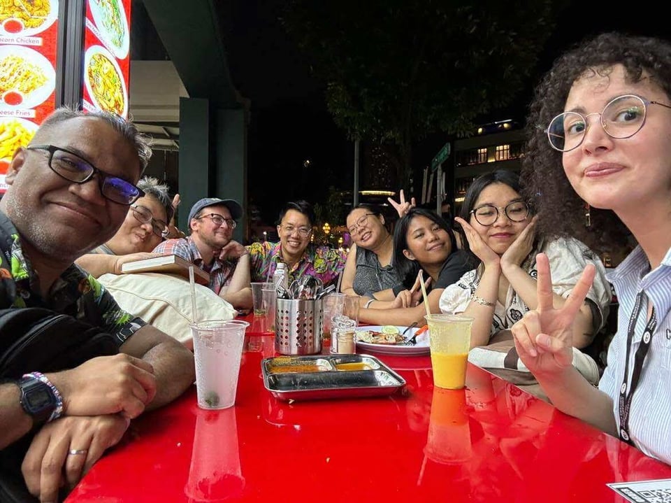 A group of us sitting around a mamak's red table at night.