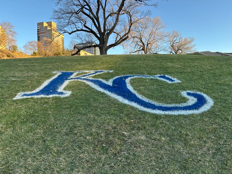 photo of grassy hill with the Kansas City Royals' KC logo painted on in blue with a white outline