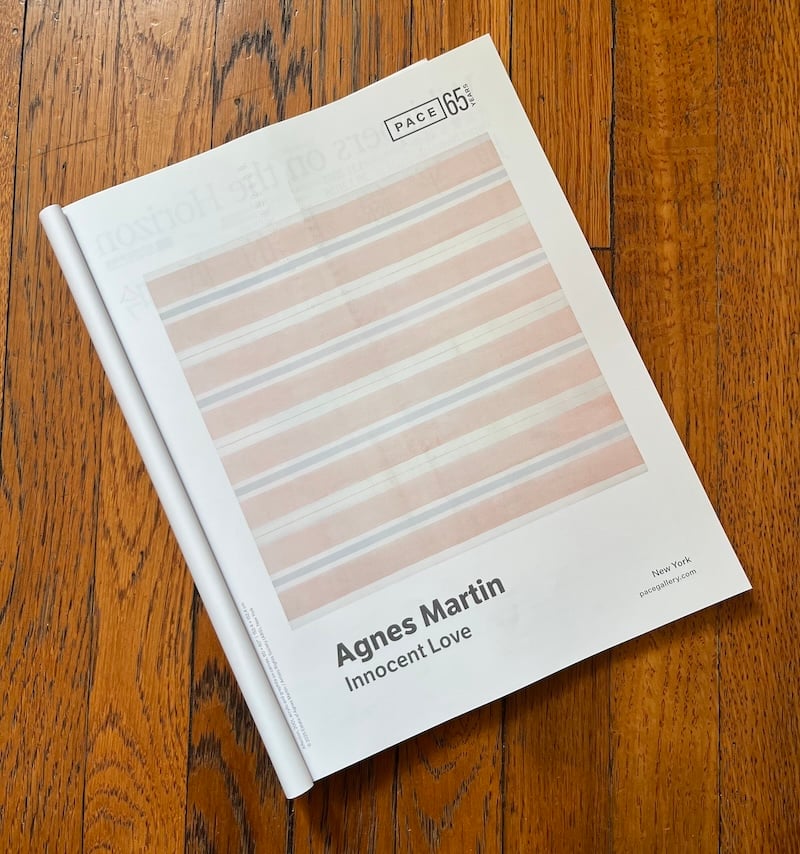 Magazine open to an advertisement for Pace Gallery's exhibition of works by Agnes Martin, "Innocent Love" featuring a square painting of pink, white, and light blue horizontal stripes.
