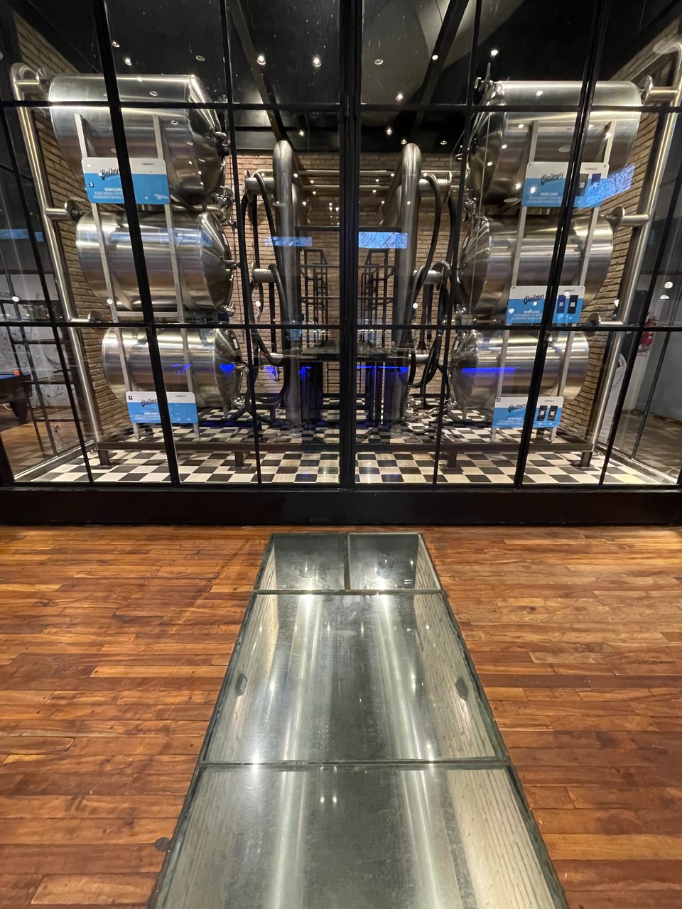 Six large tanks of beer are on display behind a large glass wall.