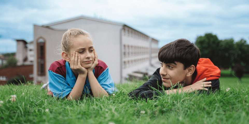 A boy and girl laying in the grass.