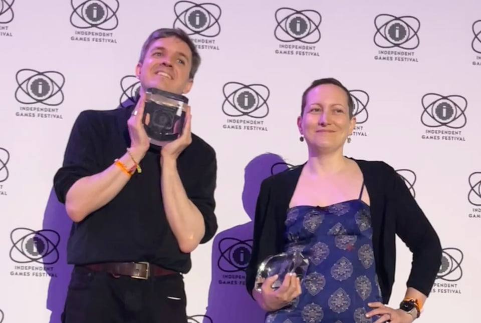Jess and AP Thomson posing with IGF trophies in front of a backdrop