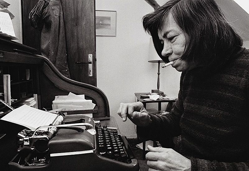 Black and white photograph of Patricia Highsmith at a manual typewriter. She's wearing a striped sweater and has a cigarette in her mouth, which I'm sorry looks cool.