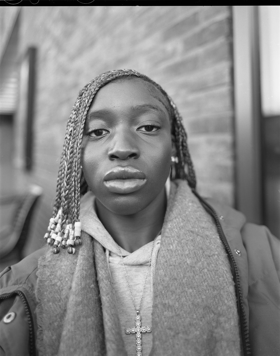 A portrait of a teenage Black girl looking directly at the camera