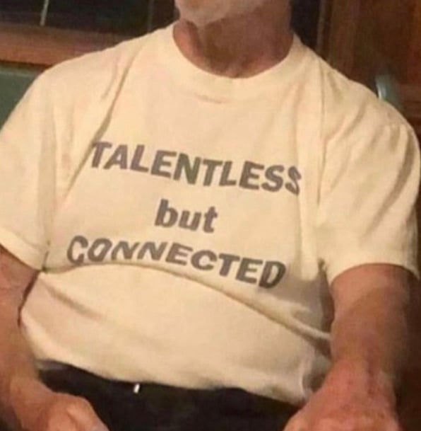 a man wearing a shirt that reads "talentless but connected"