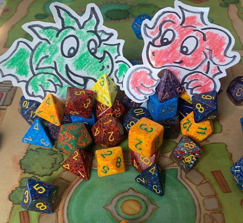 Colourful dice resting on a game board with drawings of two dragons