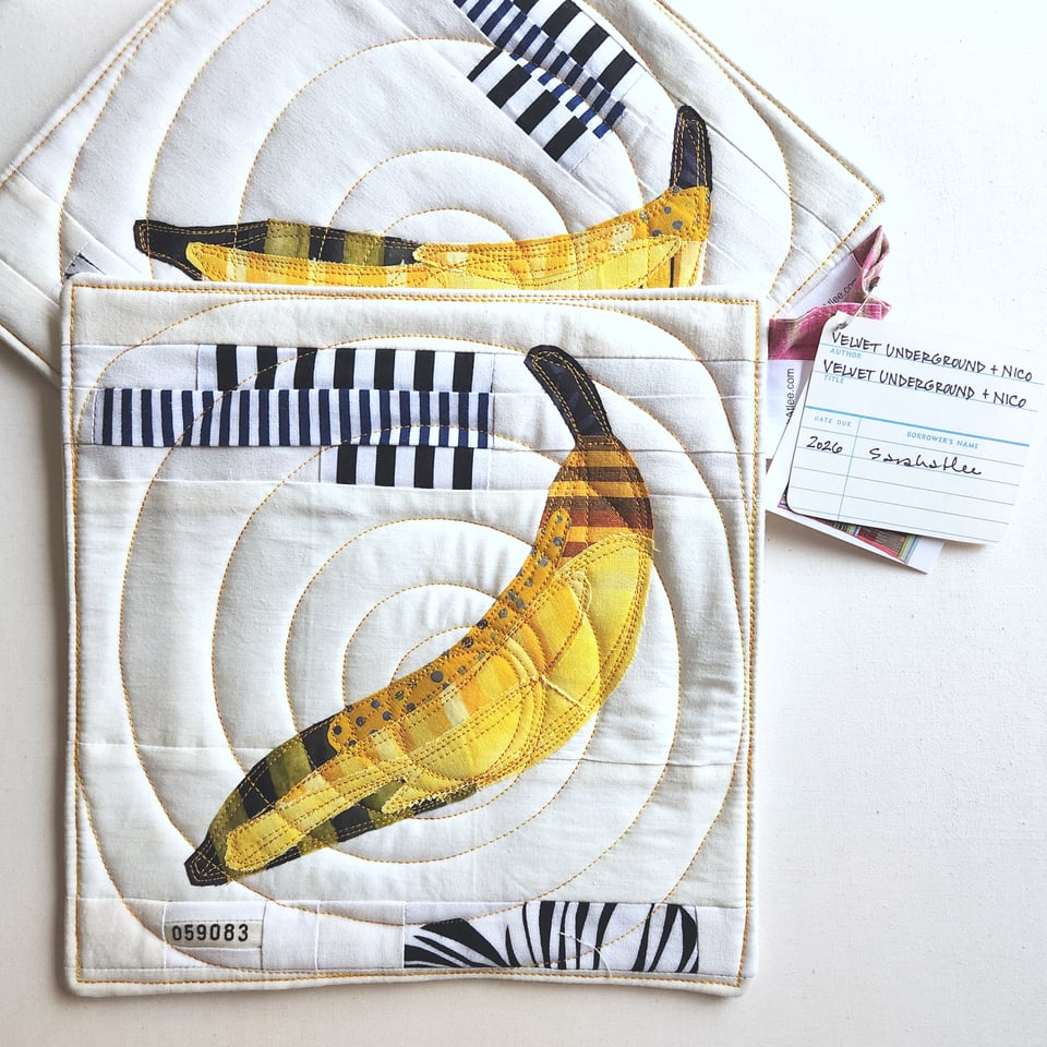Photo of a pair of finished quilted potholders. The design is Sarah's interpretation of the cover of the self-titled album by The Velvet Underground & Nico, produced and designed by Andy Warhol. It's a picture of a banana.