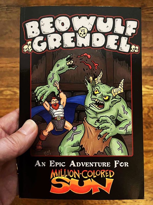 A physical copy of Beowulf Vs. Grendel, a digest-size book, held in my hand. The cover shows Beowulf ripping Grendel's arm off. it's a lovely image by Josh Burnett.