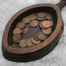 an old style collection plate, full of coins, used to collect donations after a church sermon