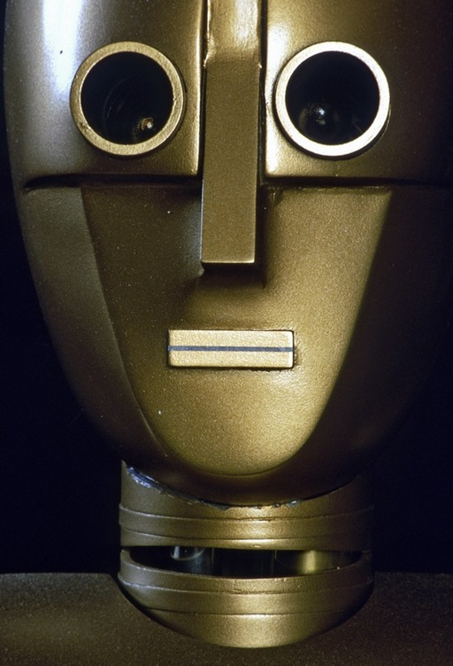 A close-up portrait of a gold robot with minimal design and facial features.