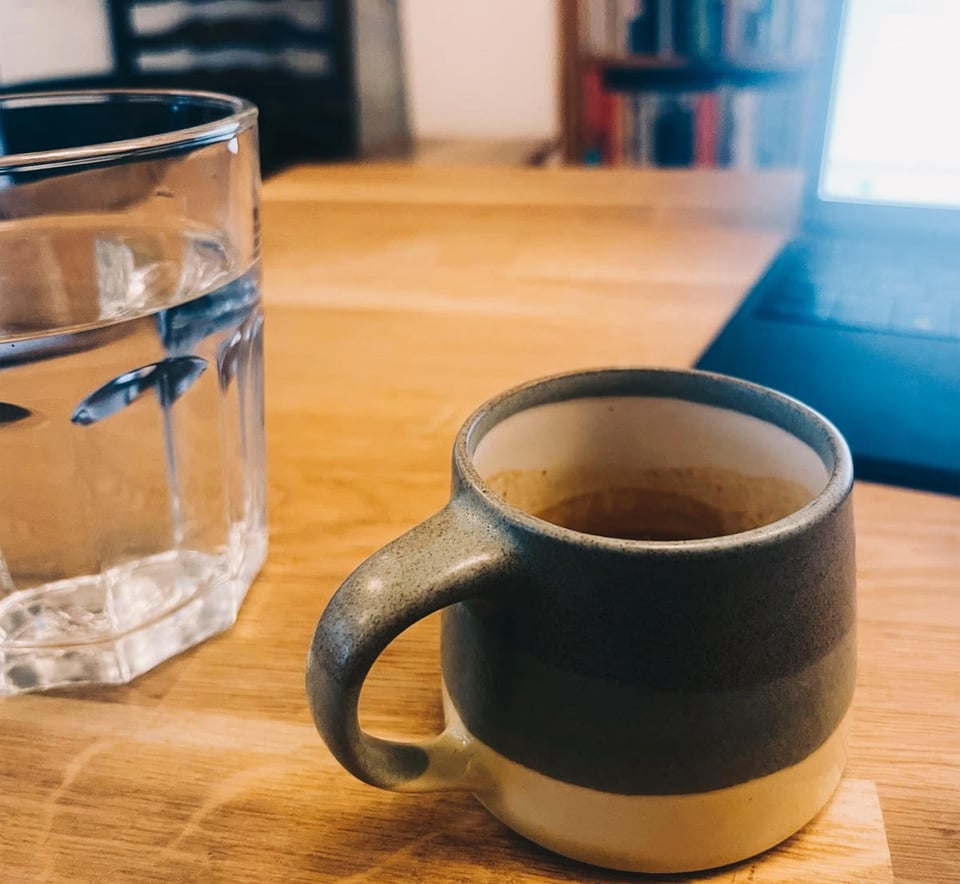 a cup of coffee on a table next to a laptop