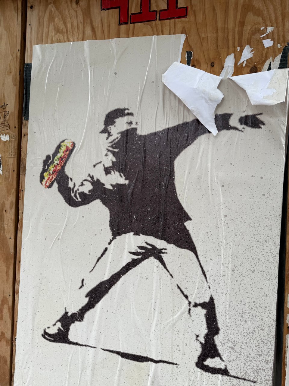 photo of a b/w poster of a protestor throwing a Molotov cocktail, but instead of the firebomb, he's got a sandwich from Subway