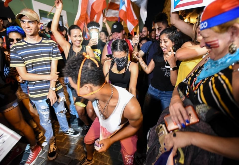 A young man twerks among other protesters in the streets of San Juan