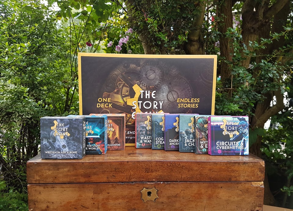A picture of a large box behind several smaller boxes. They are The Story Engine Deck box as well as its expansions.