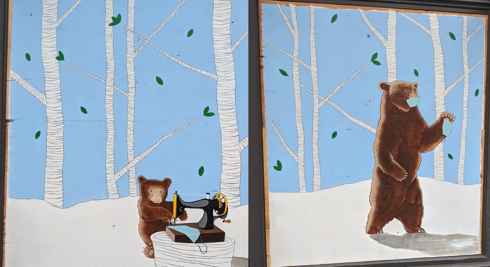 A diptych in a forest of white birch trees with snow underfoot and blue sky behind. A bear sews a blue mask on a sewing machine. The mama bear, wearing a mask, goes looking for the baby bear with a brand new mask in its paw.