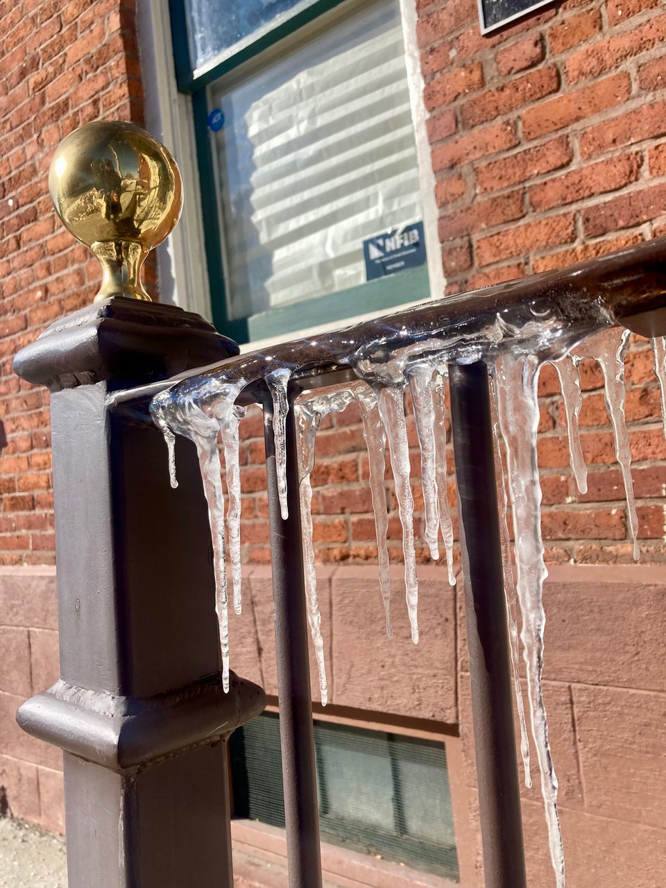 Close view of a front step railing with icicles hanging off it.