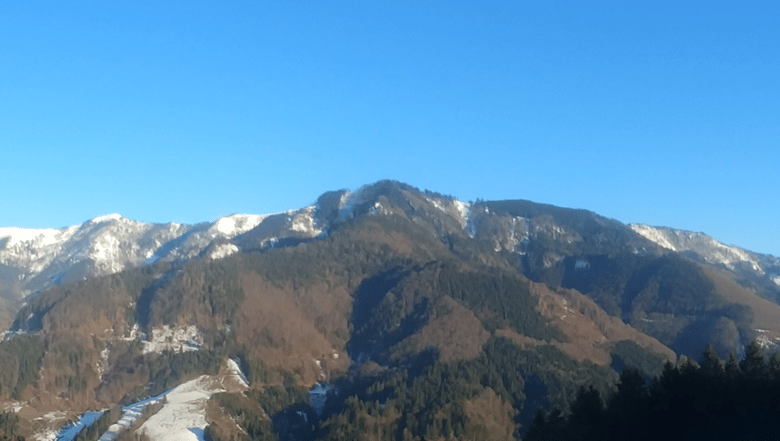 A mountainside, with spots of snow between the winter trees. A perfect spot for a hermit to meet fate.